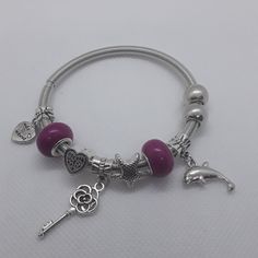 This Unique Charm Bracelet Has Two Mauve Beads Separating Several Charms; A Jumping Dolphin, Star, Angel-Winged Key Heart, And A Heart With Love Inscribed. This Is A Stretch Bracelet, So Fits Most Wrists. *Note: This Is A Listing For 1 Dolphin And Angel Wing Heart Bracelet. Silver Metal Beaded Bracelets With Heart Beads, Silver Heart-shaped Beaded Bracelets With Charms, Jumping Dolphin, Feather Cuff Bracelet, Star Angel, Key Heart, Gemstone Cuff Bracelet, Vintage Cuff Bracelet, Cz Bracelet