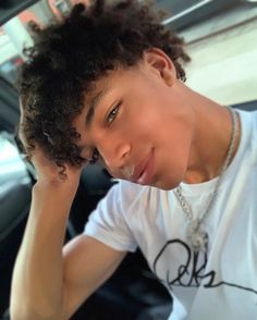 a young man with curly hair sitting in a car