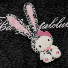 a stuffed animal with a pink bow on it's head sitting in front of a black background