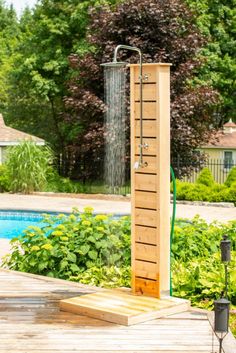 an outdoor shower in the middle of a wooden deck next to a swimming pool