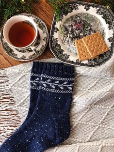 two plates with crackers on them next to a cup of tea and christmas decorations