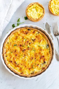 an omelet in a white dish next to two small pies on a table