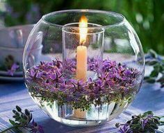 a candle is lit in a glass bowl filled with flowers