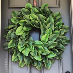 a green wreath on the front door of a house that is painted gray and has black trim