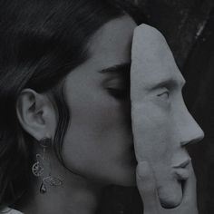 a black and white photo of a woman covering her face next to a sculpture of a man's head