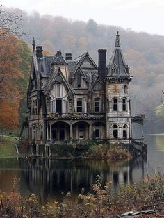 an old abandoned house sitting on top of a lake in the middle of autumn time