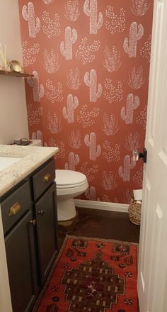 a bathroom with cactus wallpaper and rug