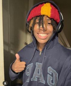 a young boy with dreadlocks wearing a hoodie and giving the thumbs up