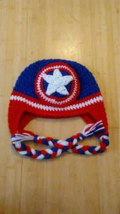 a crocheted captain america hat with braids on the side and a star in the center