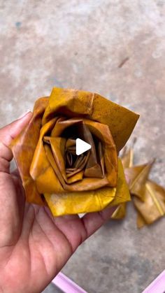 someone is holding a paper flower in their left hand and it looks like an origami rose