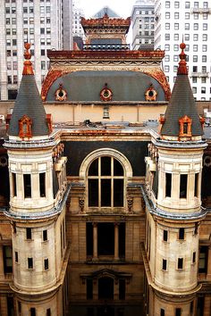 an old building with two towers in the middle of it and tall buildings behind it