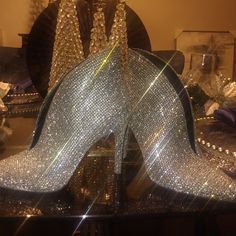 a pair of silver high heeled shoes sitting on top of a table next to a mirror