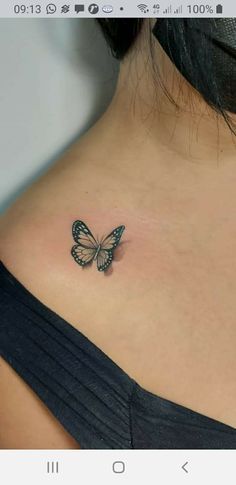 a small butterfly tattoo on the back of a woman's shoulder and chest area