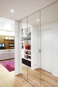 a living room filled with furniture next to a white wall and wooden floored floors