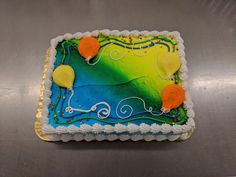 a birthday cake decorated with balloons and swirls on a silver tableclothed surface