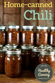 some jars filled with food sitting on top of a wooden table next to a sign that says home - canned chili