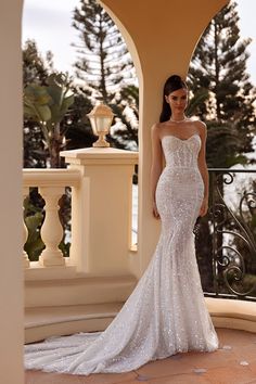 a woman standing in front of a balcony wearing a wedding dress with sequins on it