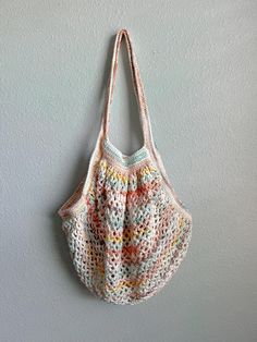 a crocheted bag hanging on the wall in front of a gray painted wall