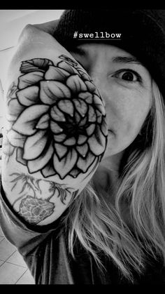 a woman is holding her hand up to her face with a flower tattoo on it