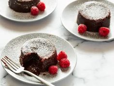 three plates with cakes and raspberries on them