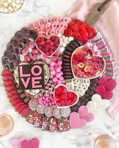 a platter filled with lots of different types of candies and hearts on top of a table