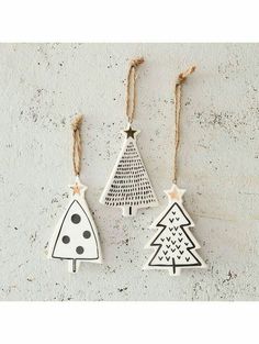 three wooden christmas trees hanging from twine strings on a white wall with black dots