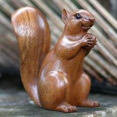 a wooden squirrel statue sitting on top of a rock