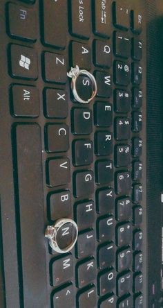 two wedding rings sitting on the keys of a computer keyboard