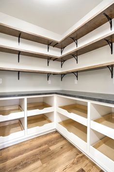 an empty walk in closet with white shelving and wooden shelves on the wall,