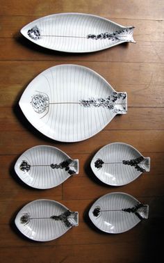 four white plates sitting on top of a wooden table covered in black and white designs