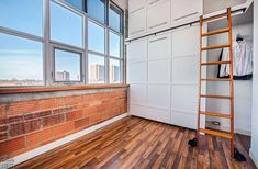 an empty room with wooden floors and white walls, has a ladder leaning against the wall