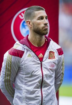 a man standing in front of a red and white flag with his hands on his hips