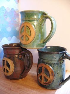 three coffee mugs with peace signs painted on them