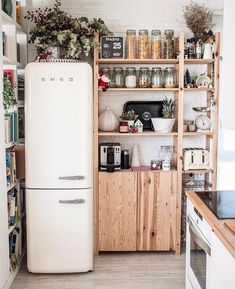 a white refrigerator freezer sitting in a kitchen next to a wooden shelf filled with food