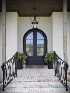 an entry way with two plants and a lantern hanging from the ceiling over it's doorway