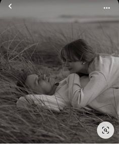 a black and white photo of two women laying in the grass with their heads touching each other