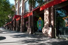 an empty street lined with brick buildings and decorated shops on the side of each building