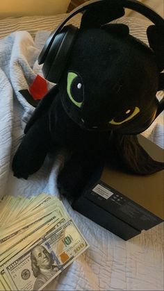 a stuffed animal with headphones and money on a bed