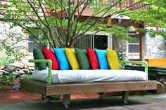 a couch made out of wood with colorful pillows on it