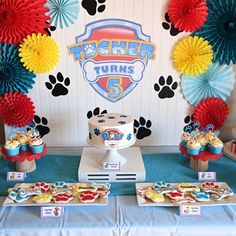 a table topped with cupcakes and cakes covered in frosting next to paper fans