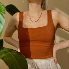 a woman with her hands on her hips wearing a brown tank top and white shorts