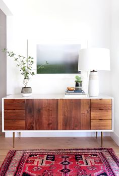 a room with a rug, table lamp and painting on the wall in front of it