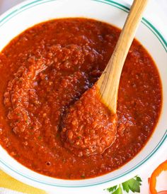 a white bowl filled with sauce and a wooden spoon