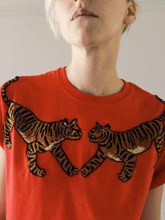 a woman wearing an orange shirt with two tigers on it