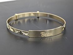 A beautiful 100% genuine solid 9ct Yellow Gold ID Baby Bangle with a pattern. This is the perfect baby gift, that lasts as a keepsake.  The name can be engraved on the Name Plate. The longer the name the smaller the engraving will be.  Choose Any Name to be engraved. We offer a choice of fonts. Please see below. Exceptional quality: can extend slightly to grow with baby. It has a Sparkling high polished finish. Complimentary Gift Box Included. The perfect gift for the new born baby . Ideal for b Personalized Gold Jewelry For Special Day, 14k Yellow Gold Bracelets For Birthday, Adjustable 14k Gold Bracelet, Adjustable Hallmarked White Gold Bracelet, Gold Name Bracelet With Hallmark For Gifts, Gold Name Bracelet With Hallmark As Gift, Adjustable Gold Name Bracelet With Hallmarks, Gold Round Name Bracelet, Adjustable 14k Gold Bracelet For Birthday