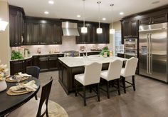 a kitchen with dark wood cabinets and white chairs