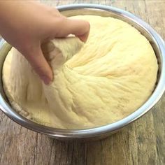 someone is kneading dough into a metal bowl