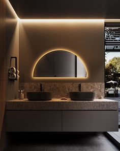 a bathroom with two sinks under a mirror and lights on the wall above it, next to a large window