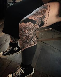 a person with tattoos on their legs sitting in a chair