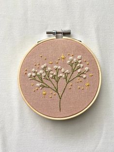 the embroidery is being worked on by someone using scissors and thread to make it look like they are holding flowers